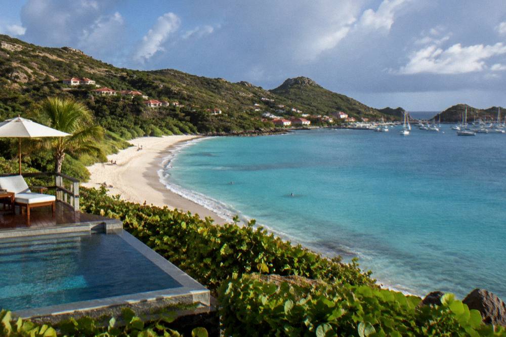 A hillside villa with a pool overlooking a Caribbean bay at golden hour