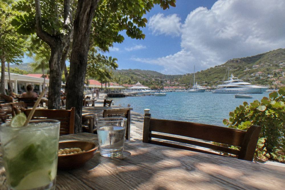 Evening tables set along a quay with white yachts moored in a small harbour