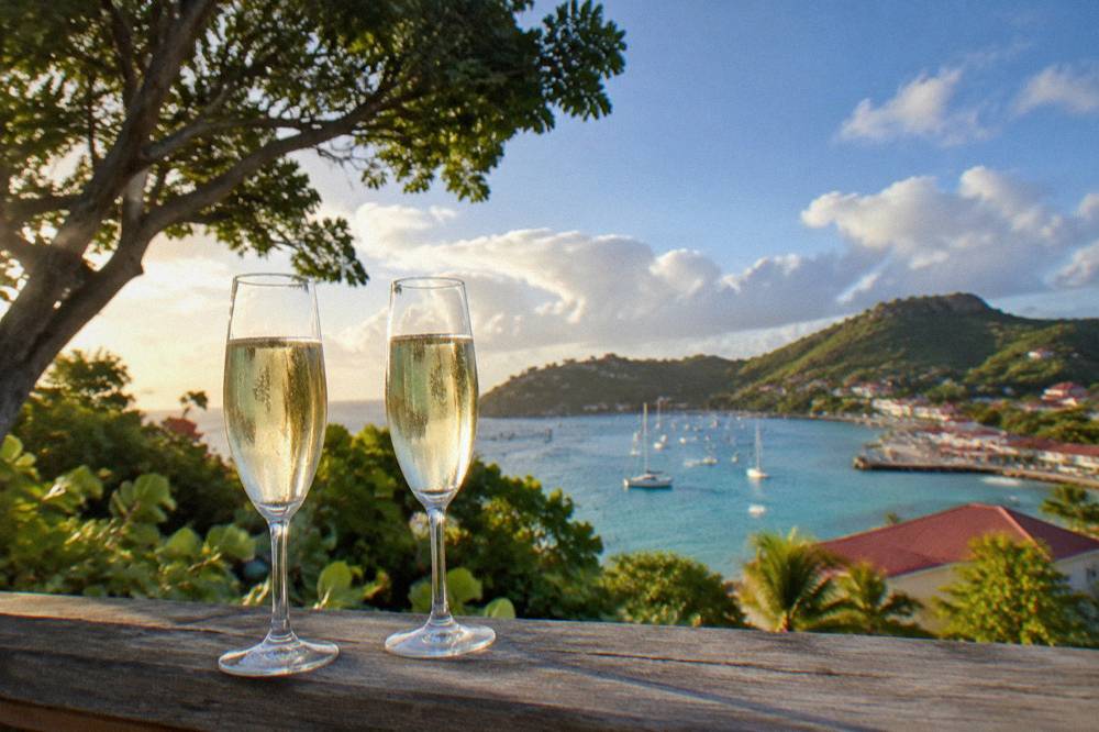 Two glasses of champagne on a railing at sunset over a Caribbean bay