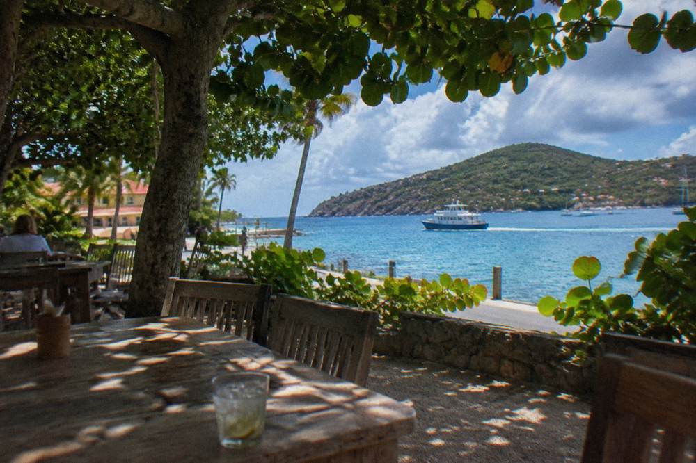 A small ferry boat crossing open blue water toward a green island