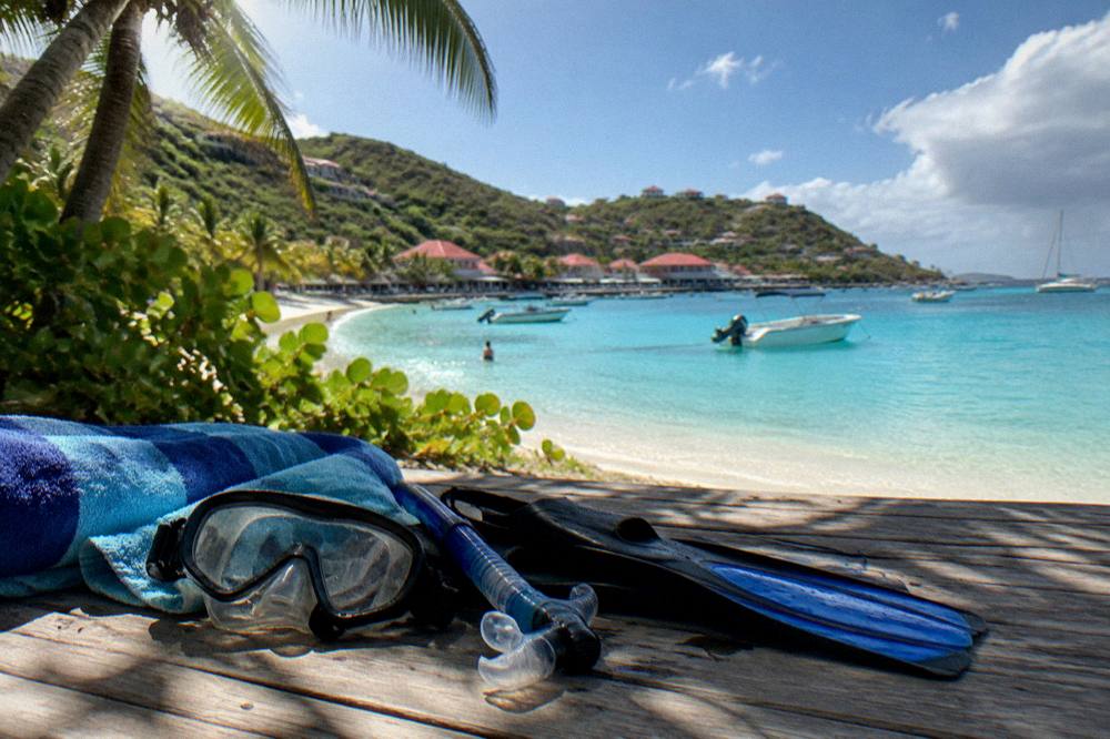 Snorkel masks and beach gear laid out on a wooden deck beside a folded towel