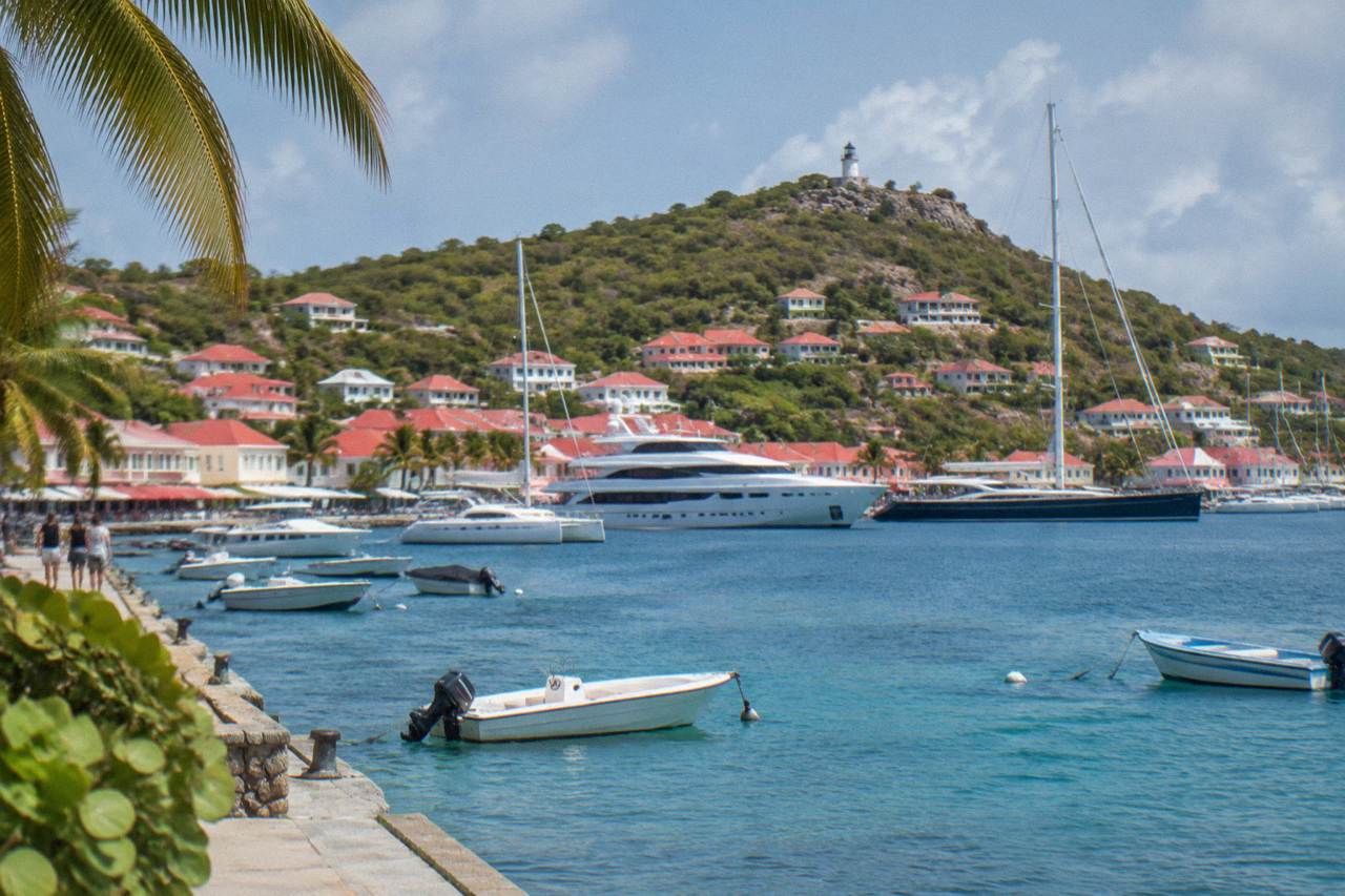Yachts anchored in Gustavia harbor with red-roofed buildings on the hillside behind them