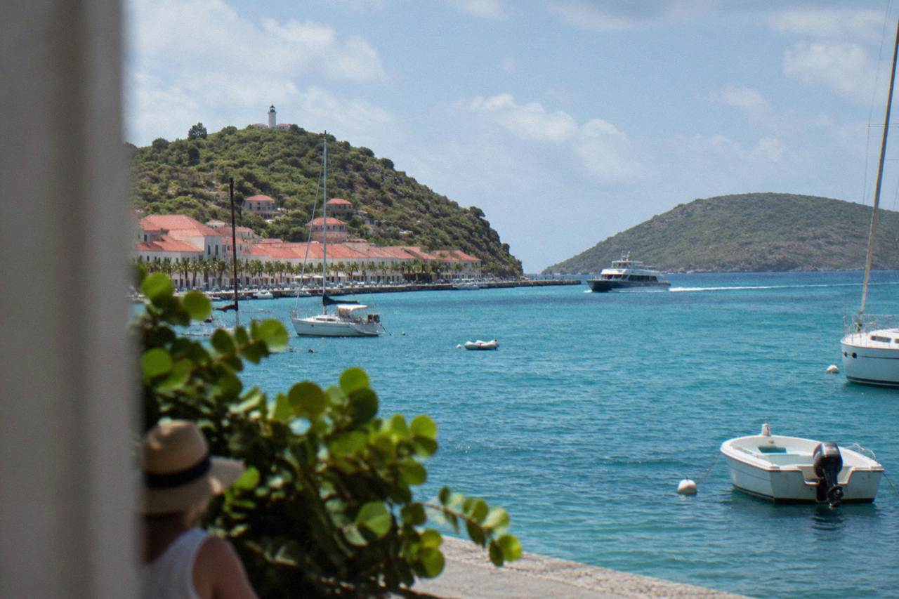 A passenger ferry cutting across open blue Caribbean water toward a green hilly island