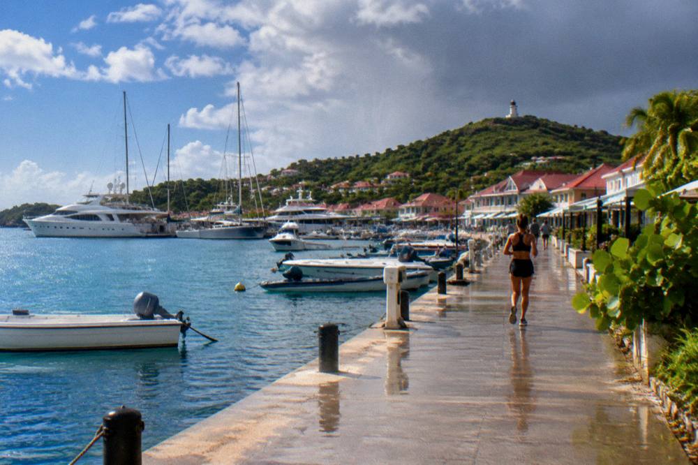 Yachts lit at night in a Caribbean harbour with hills behind