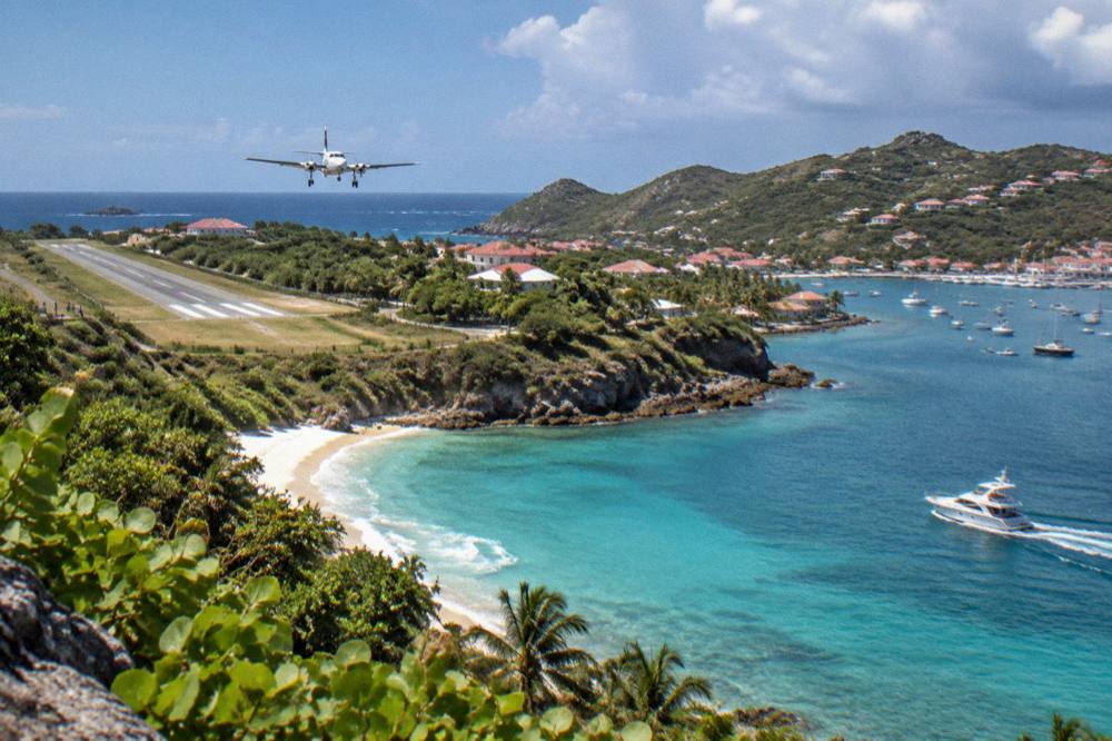 A private motor yacht cruising along a green Caribbean coastline in bright light