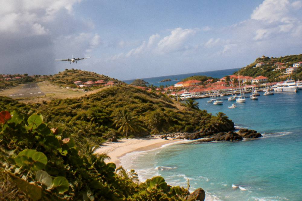 A harbor town with red roofs and white yachts moored along a stone quay