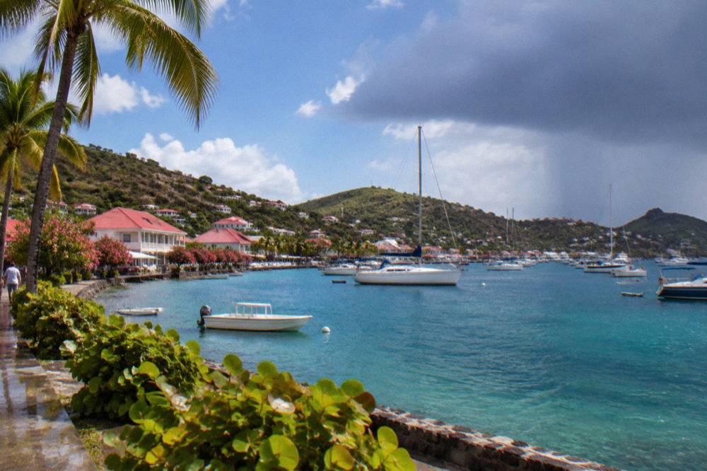 Small Caribbean harbor town with red roofs and anchored sailing boats