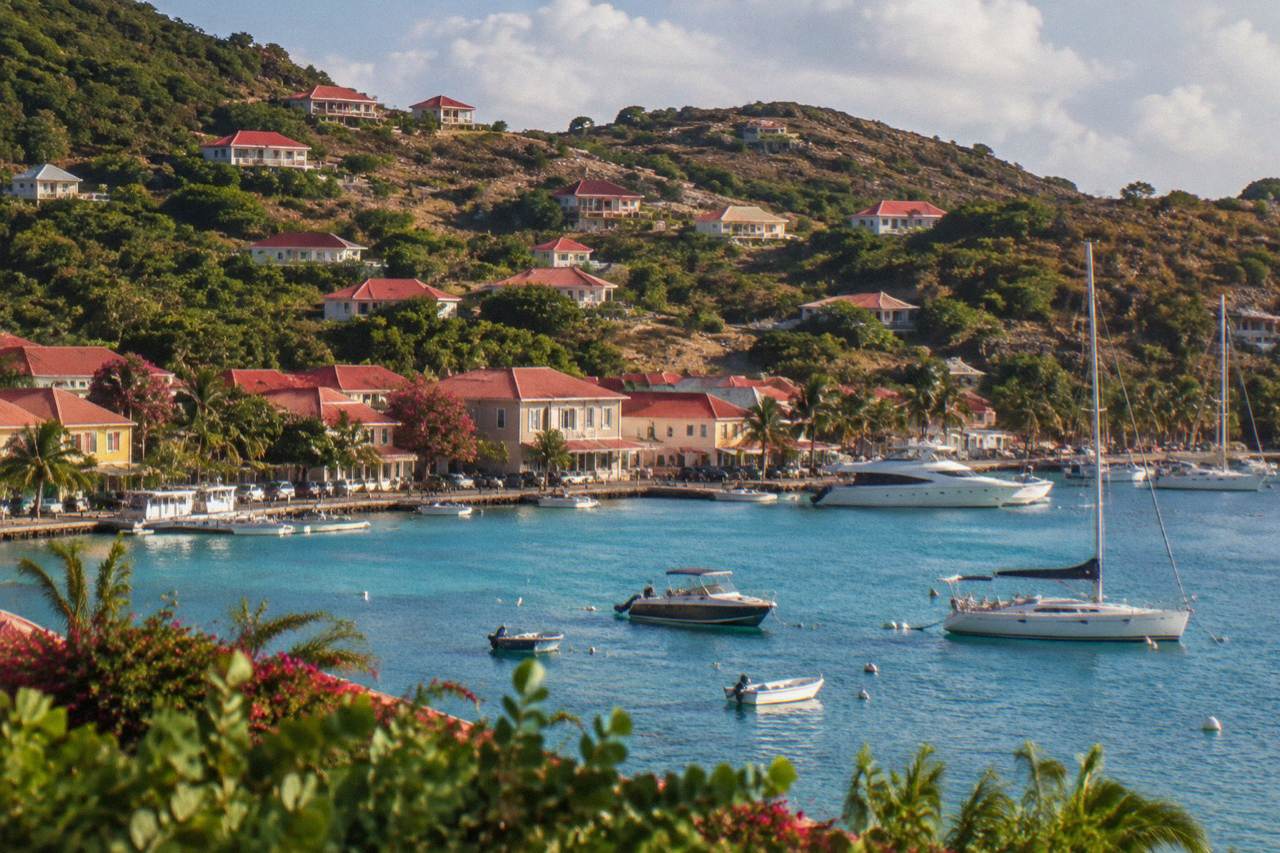 Red-roofed houses on a green hillside above a turquoise Caribbean bay on St Barts