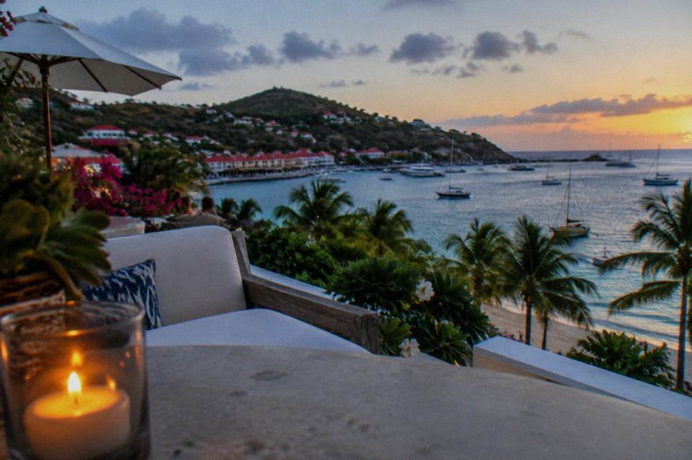A small upscale hotel terrace above a palm-lined beach at sunset