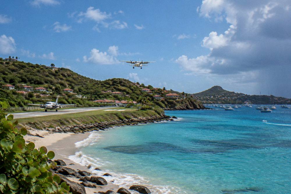 A small turboprop aircraft on the short runway at St Barts airport beside the beach