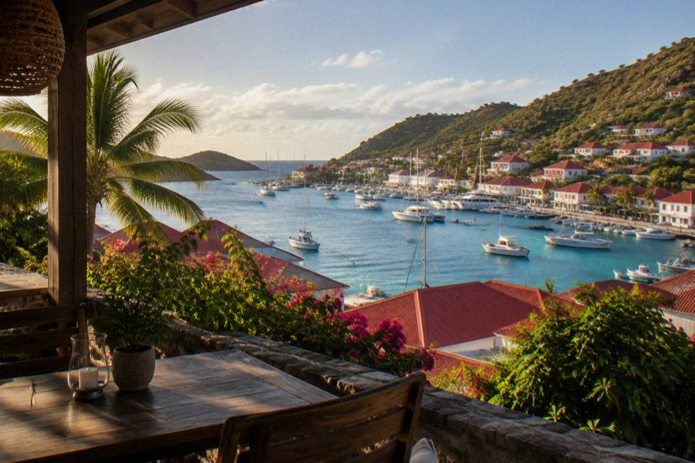 A shaded terrace with a view over rooftops to the sea at golden hour