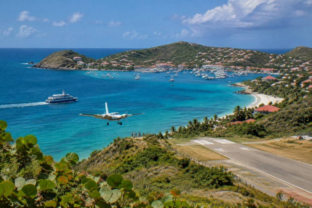 A passenger ferry crossing open blue water toward a green island with a harbour town