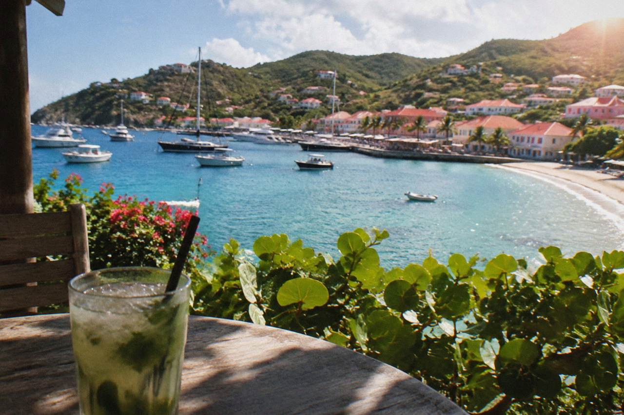 A curved Caribbean beach below green hills on the island of St Barts