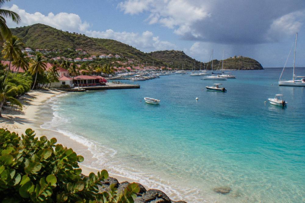 Turquoise water meeting a pale sand beach on St Barts with a headland in the distance