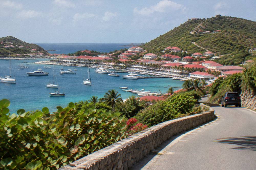 An open coastal road winding between green hills above the sea in St Barts