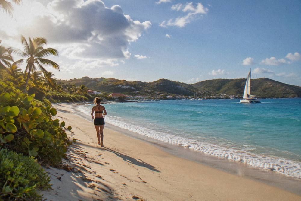 A sailing catamaran on open blue water heading toward the coast of St Barts