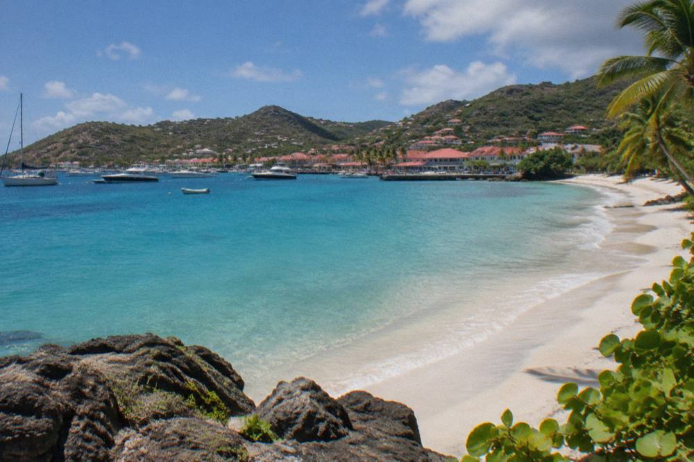 An empty crescent of white sand backed by green hills and dunes at a Caribbean beach