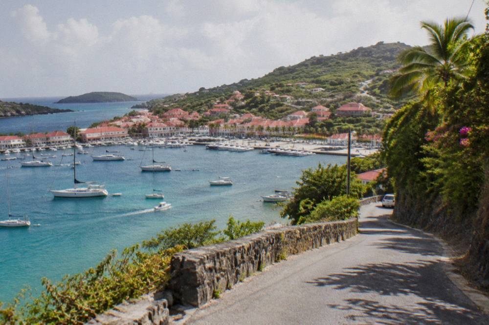 A narrow winding road climbing a green hill above the sea on a small tropical island