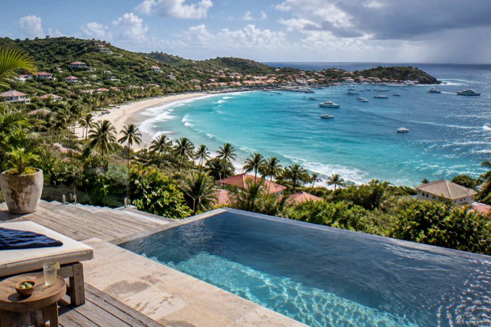 A hillside villa terrace with an infinity pool looking over a bay