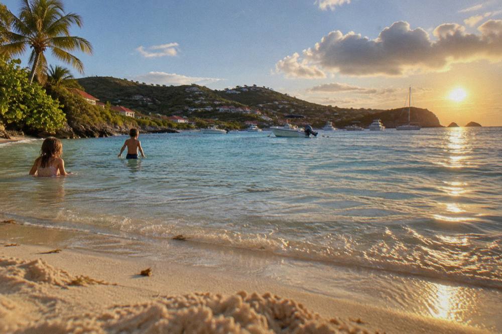 Children playing in shallow water at the edge of a calm sandy beach