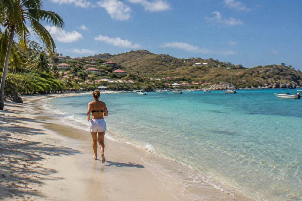 A wide sandy beach with palm shade and gentle shallows along the shore