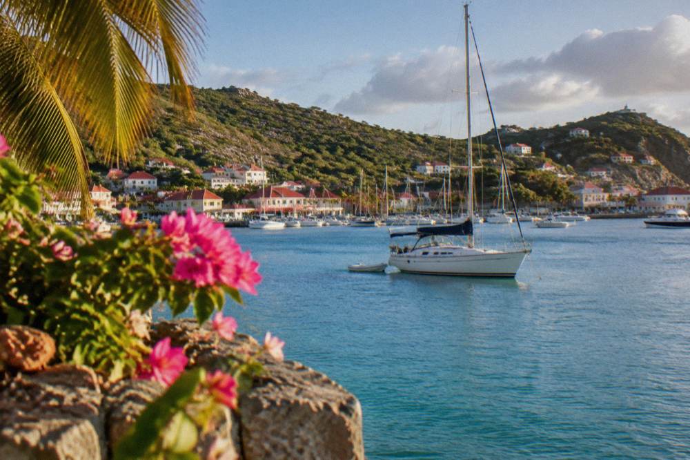 A sailboat anchored in a quiet bay with green hills behind