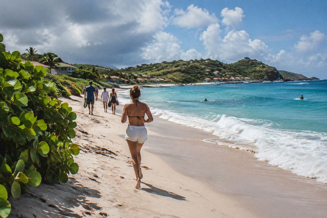 A group of friends walking down a hillside road toward a turquoise Caribbean bay