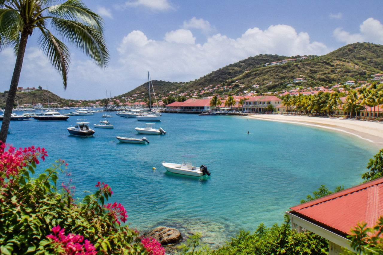 A calm turquoise bay on St Barts with a curve of sand and green hills behind it