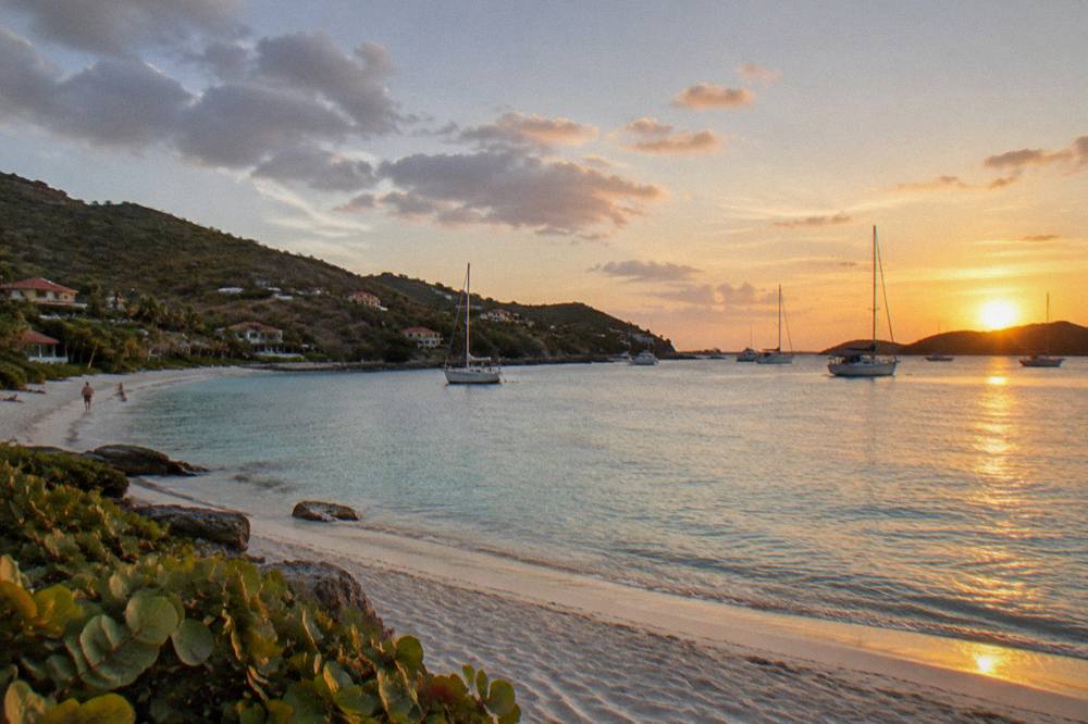 Sunset light over a Caribbean harbour with yachts at anchor and hills beyond