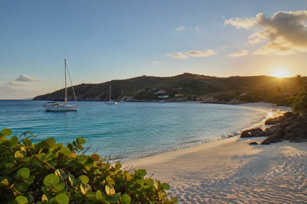 Sailing boat anchored in a quiet bay with green hills at Colombier on the northwest tip of St Barts