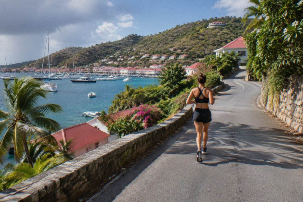 A narrow winding road climbing a green hillside above the sea