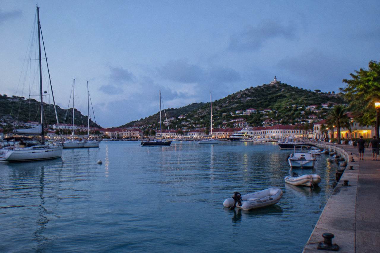 Sailboats moored in Gustavia harbor at golden hour with hills behind the town