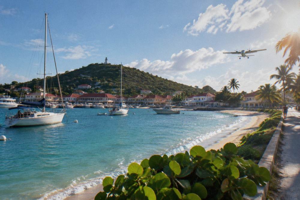 A small turboprop aircraft on final approach over a beach road toward the runway at Saint-Jean