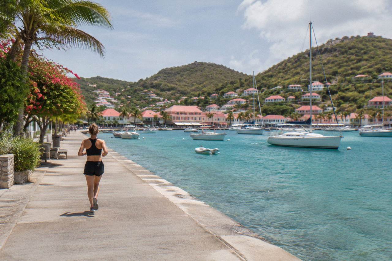 Sailboats anchored in turquoise water below the green hills of St Barts