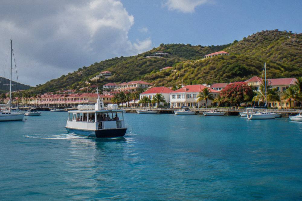 Small ferry approaching the harbour buildings of Gustavia in late afternoon light