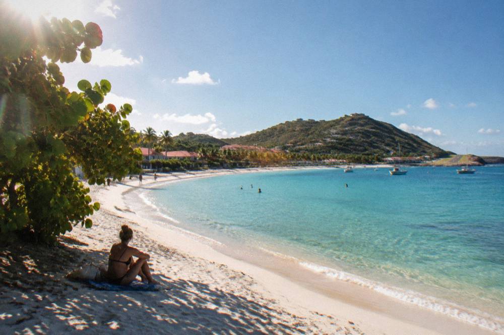 White sand beach at Saint-Jean curving toward a small runway spit under a clear sky