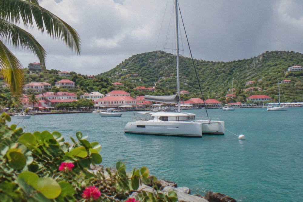 A sailing catamaran moored in grey weather off a green hillside in St Barts