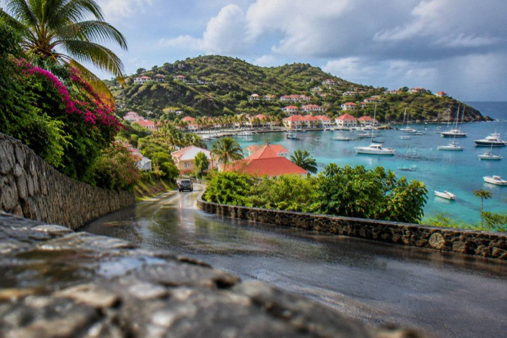 A rain-wet road winding between green hills above the coast of St Barts