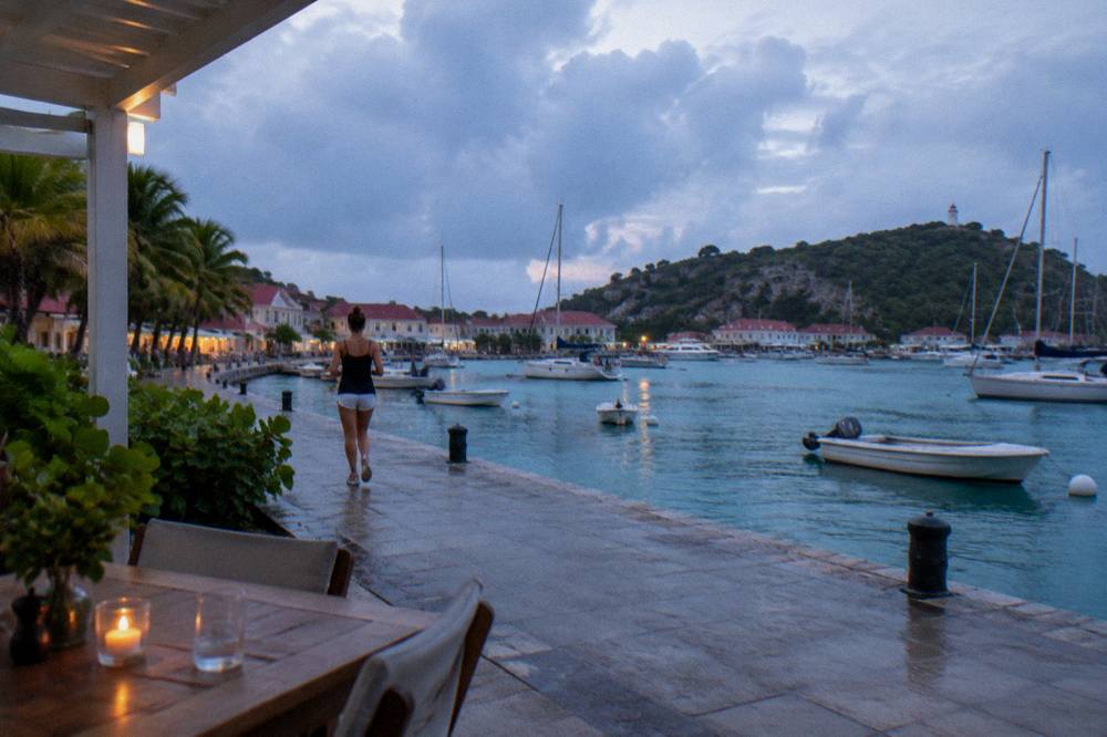 A covered terrace table with a view over Gustavia harbour under grey skies