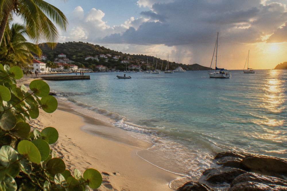 A small Caribbean harbor town with white buildings, red roofs and yachts at anchor